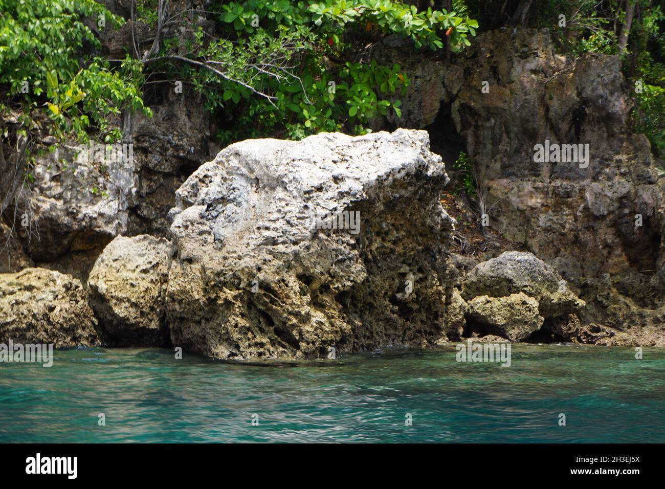 Falaises rocheuses près de l'eau bleue avec récif de corail à la plage de Talikud Island, Philippines Banque D'Images