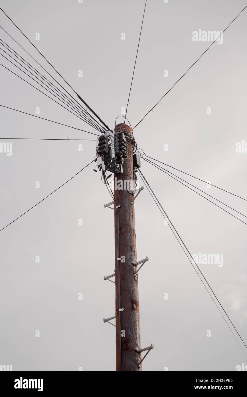 Vue à angle bas d'un poteau télégraphique en bois avec des fils menant à des maisons locales fournissant des signaux de télécommunication pour les téléphones personnels et à large bande Banque D'Images