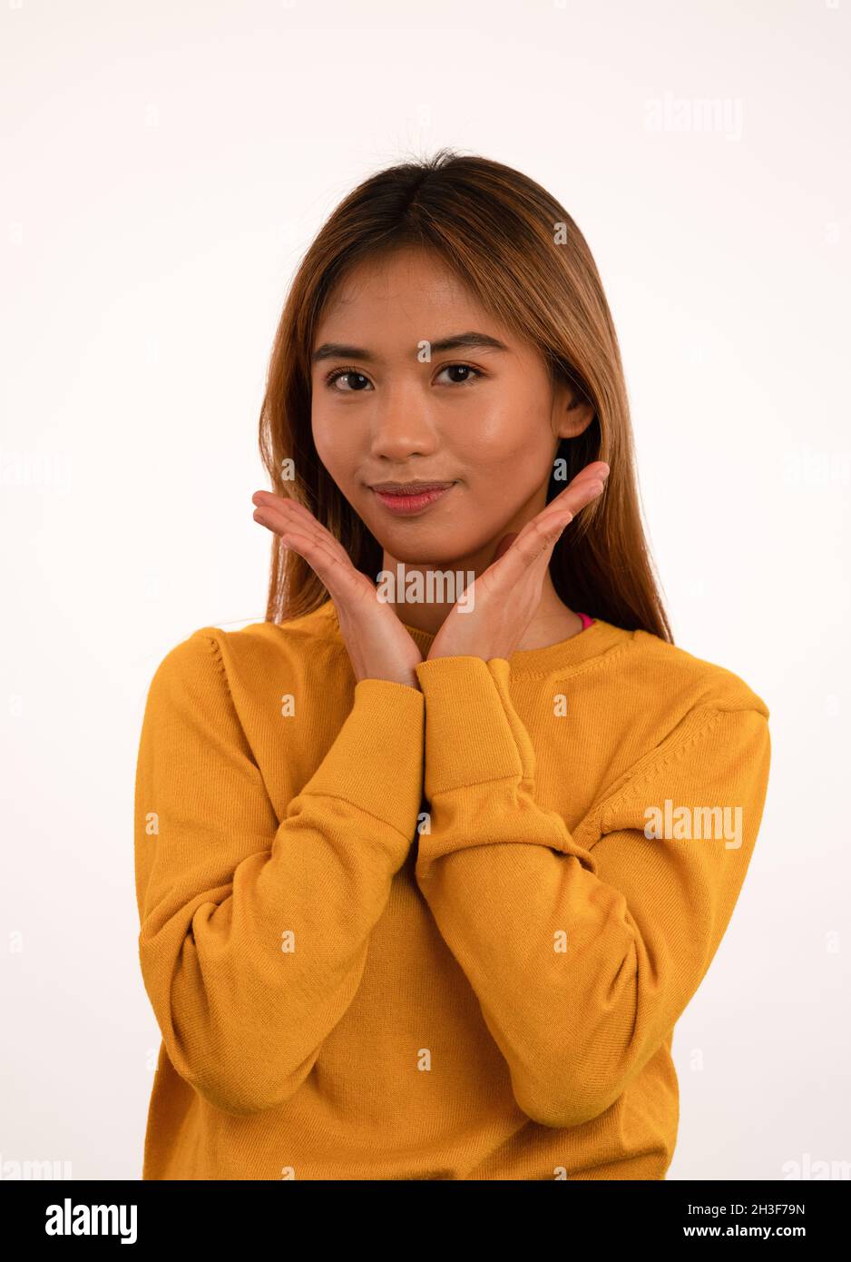 Jeune fille asiatique attrayante posant avec les mains sur le menton en studio Banque D'Images