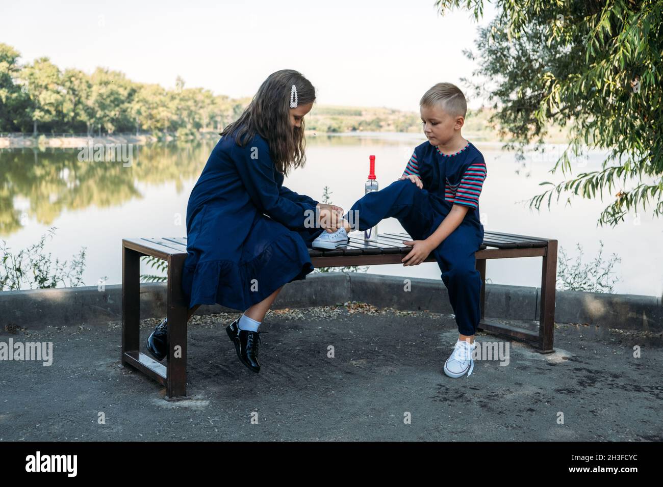 Где завязывают мальчиков. Брат и сестра на скамейке в школе. Мальчик помогает девочке фото. Мальчик завязывает шнурки девочке. Мальчик и девочка играют вместе.