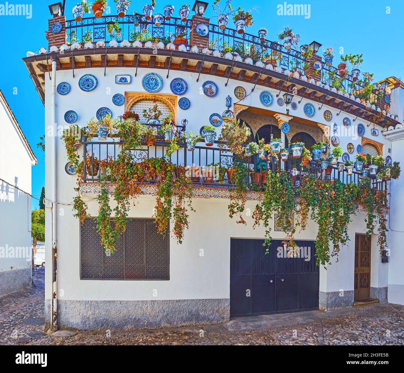 La maison ornée, décorée dans le style andalou traditionnel avec des assiettes en céramique, couverte de motifs bleus fins, plantes vertes et fleurs en pots, Al Banque D'Images
