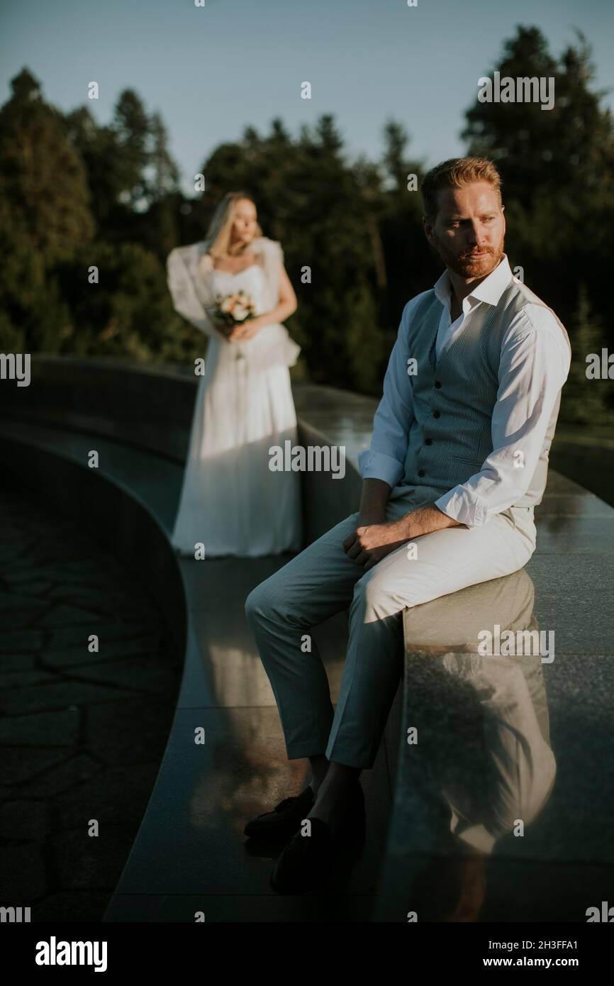 Gros plan du jeune homme nouvellement marié assis devant sa jeune mariée Banque D'Images
