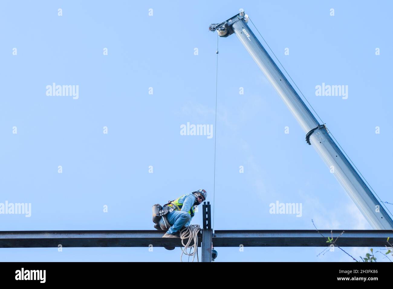 LA NOUVELLE-ORLÉANS, LA, États-Unis - 25 OCTOBRE 2021 : ouvrier de la construction glissant le long d'une poutre avec une grue en arrière-plan Banque D'Images