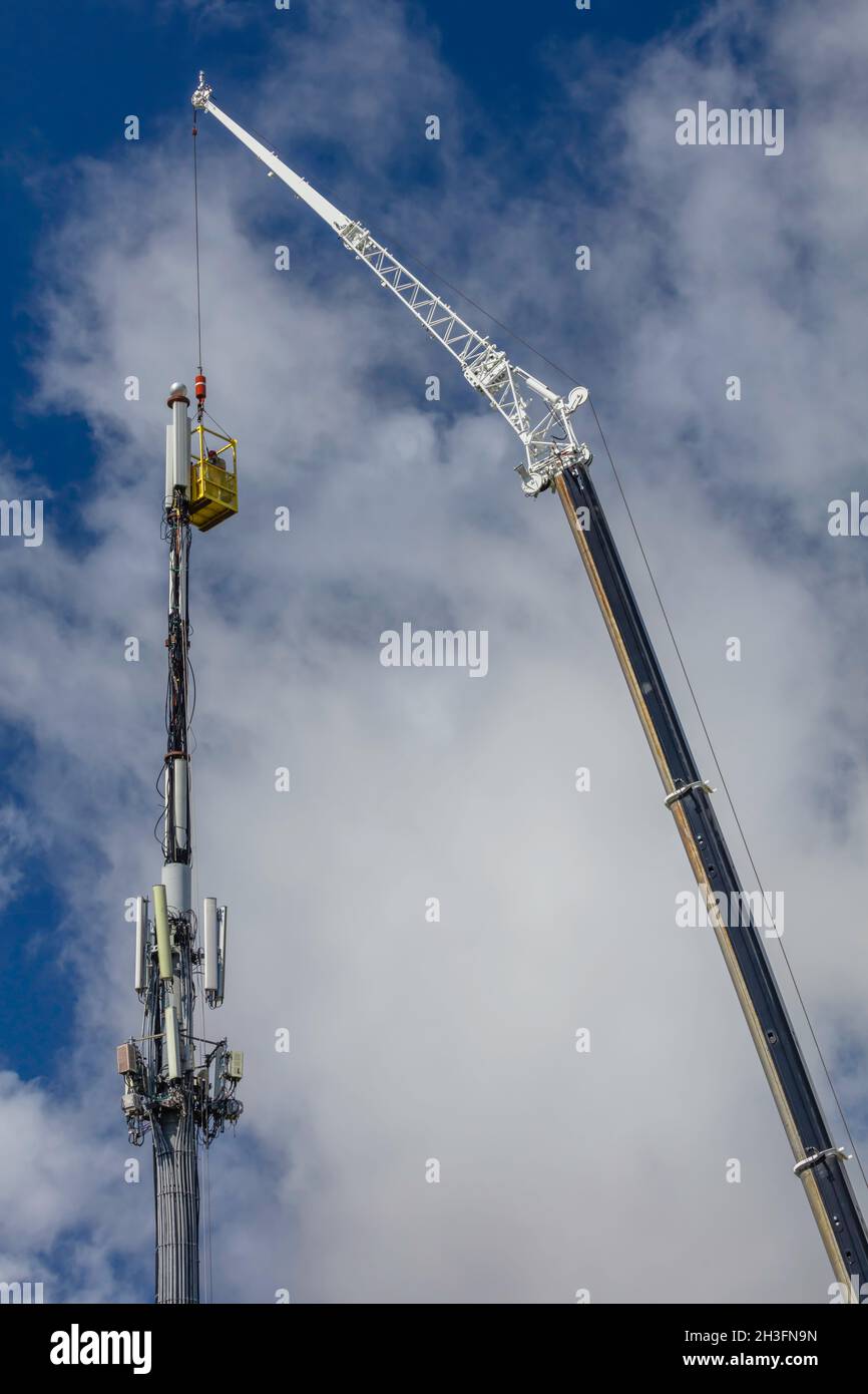 Deux techniciens travaillent depuis le panier suspendu pour effectuer des mises à niveau de la tour de téléphone portable lors du Congrès qui marchande sur les dépenses d'infrastructure. Banque D'Images