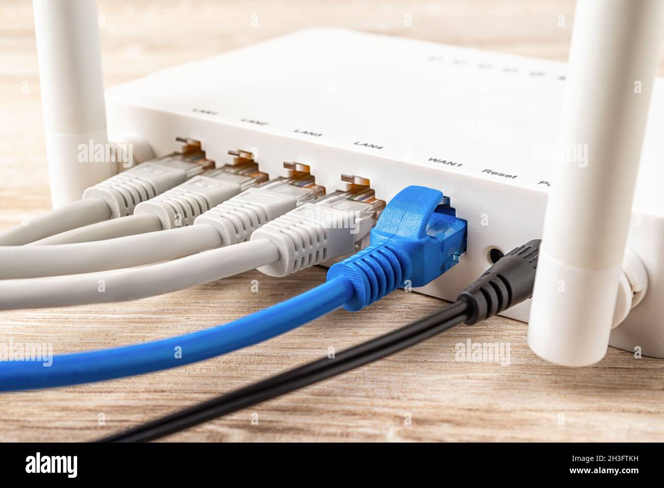 Fiches de câble réseau bleues et grises connectées au routeur sans fil  Wi-Fi blanc sur un bureau en bois.Gros plan du routeur domestique ou  professionnel fournit Internet Photo Stock - Alamy
