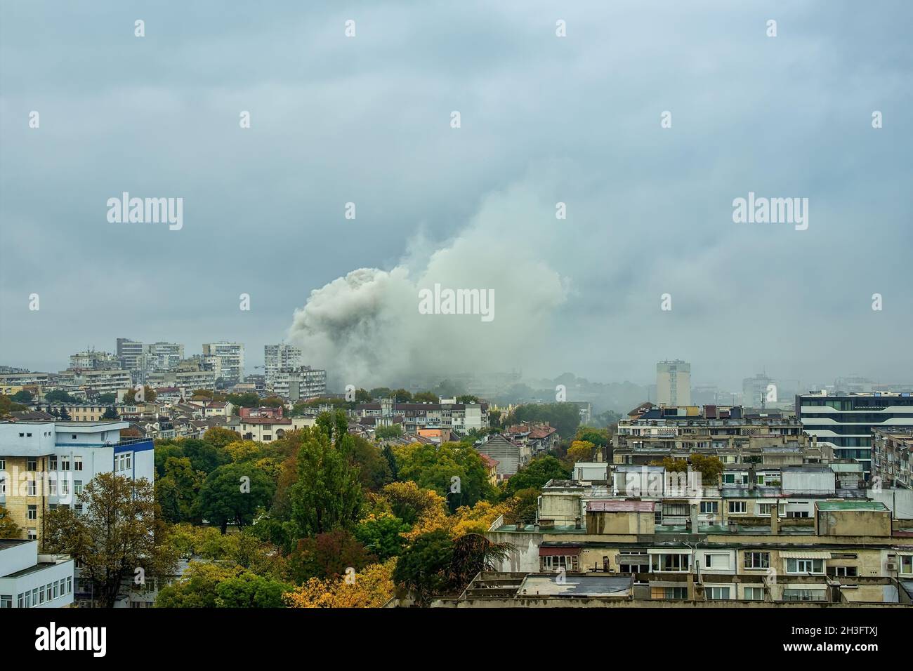 Un énorme nuage de fumée gris couvre les bâtiments pendant la lutte contre les incendies.Une grande bouffée de fumée, comme une explosion, s'élève.Vue sur la ville avec incendie. Banque D'Images