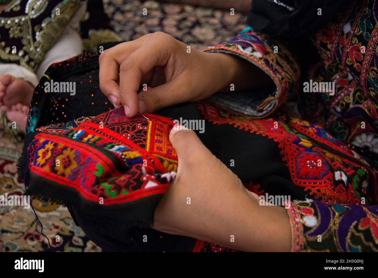 Une fille immigrée afghane en Iran est en cours de couture d'une robe. Banque D'Images