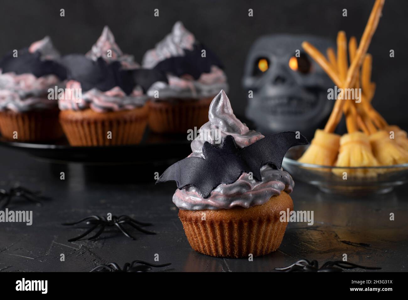 Cupcakes à la crème colorée décorée de chauves-souris de mastic et de balais de sorcière faits de fromage et de paille pour la fête d'Halloween Banque D'Images