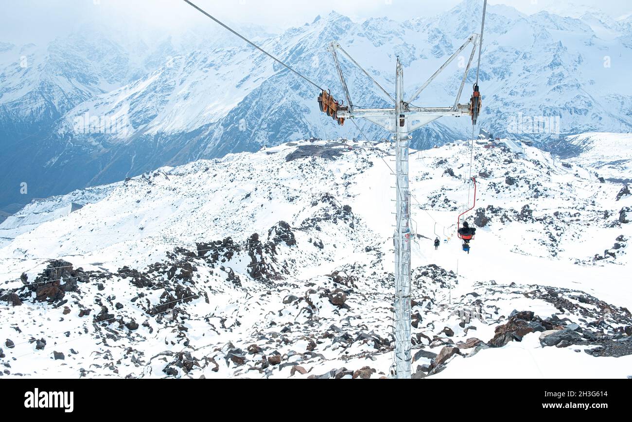 Les gens sur le téléphérique contre le fond de sommets enneigés.Station de ski.Télésiège pour touristes, snowboarders et skieurs.Elbrus Banque D'Images