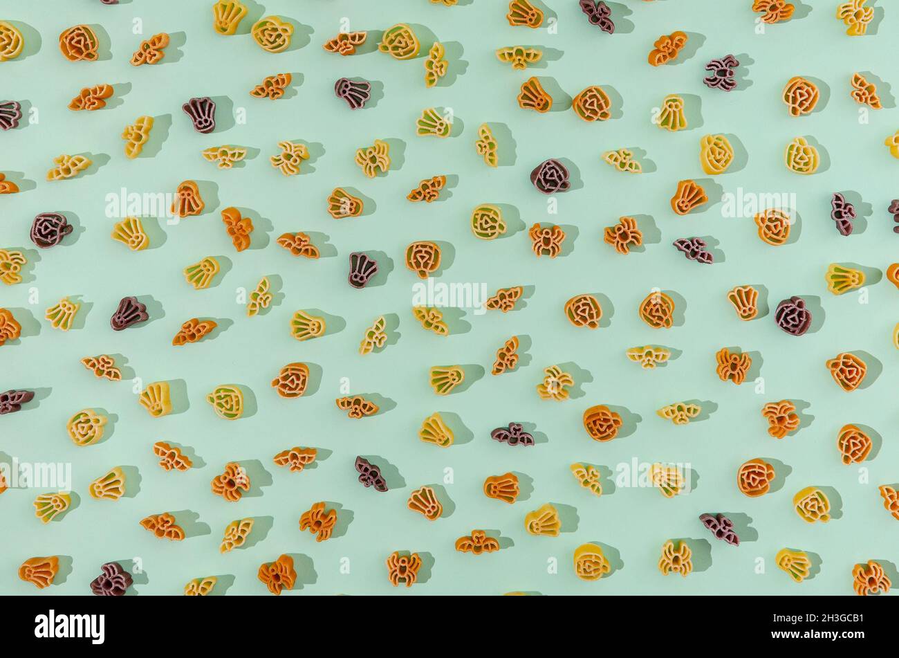 Un motif lumineux composé de pâtes en forme de symboles Halloween sur fond vert pastel.Concept créatif de nourriture ou de repas pour Halloween. Banque D'Images