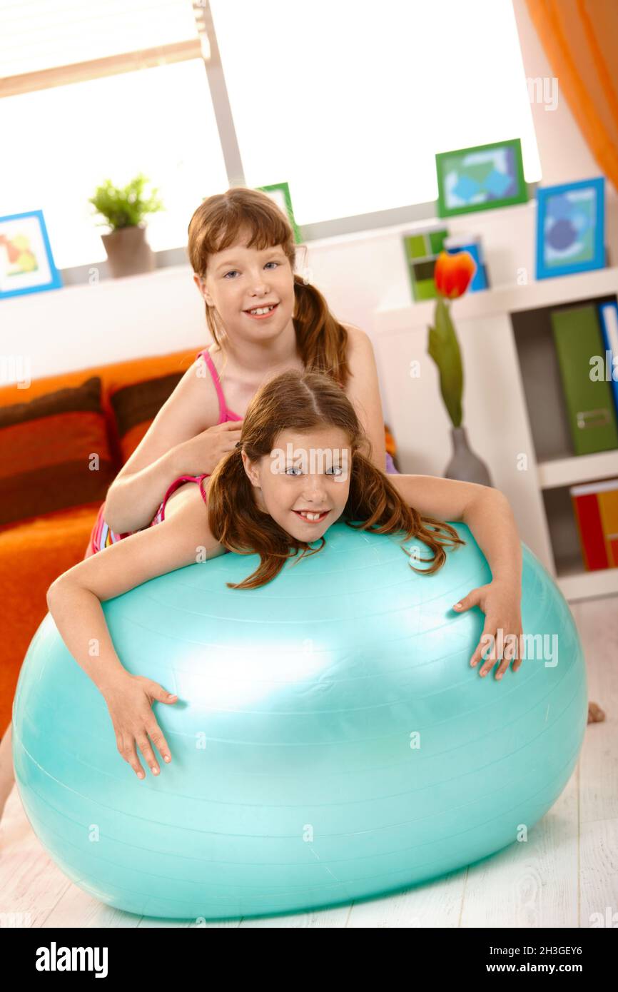 Filles jouant avec le ballon de gym dans la salle de séjour Banque D'Images