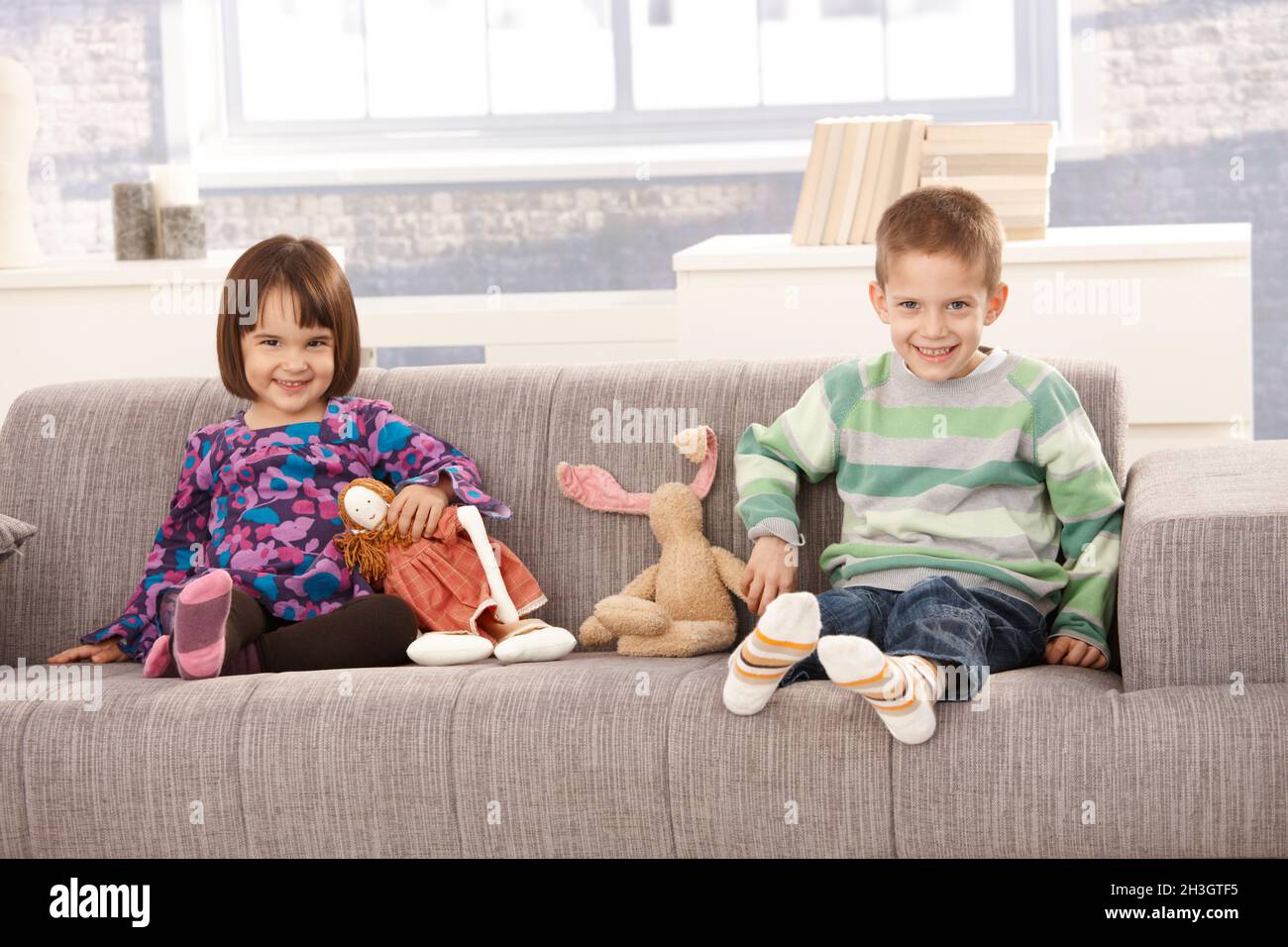 Des enfants heureux assis sur le canapé Banque D'Images