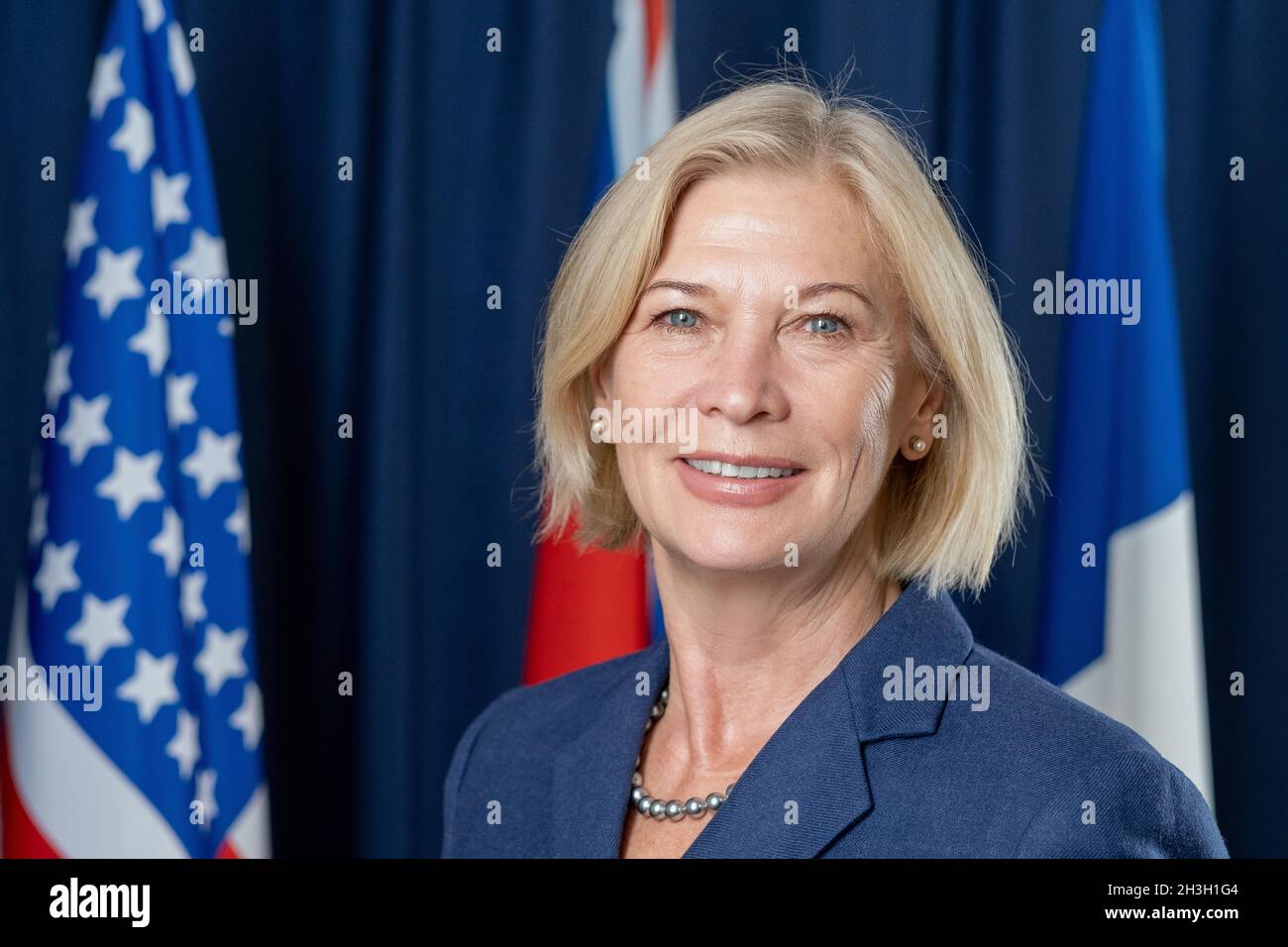 Portrait d'un membre du Congrès caucasien souriant et confiant, en perles debout contre des drapeaux nationaux Banque D'Images