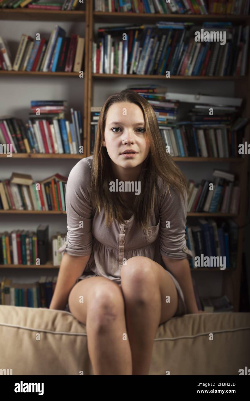 Jeune femme assise sur le canapé Banque D'Images