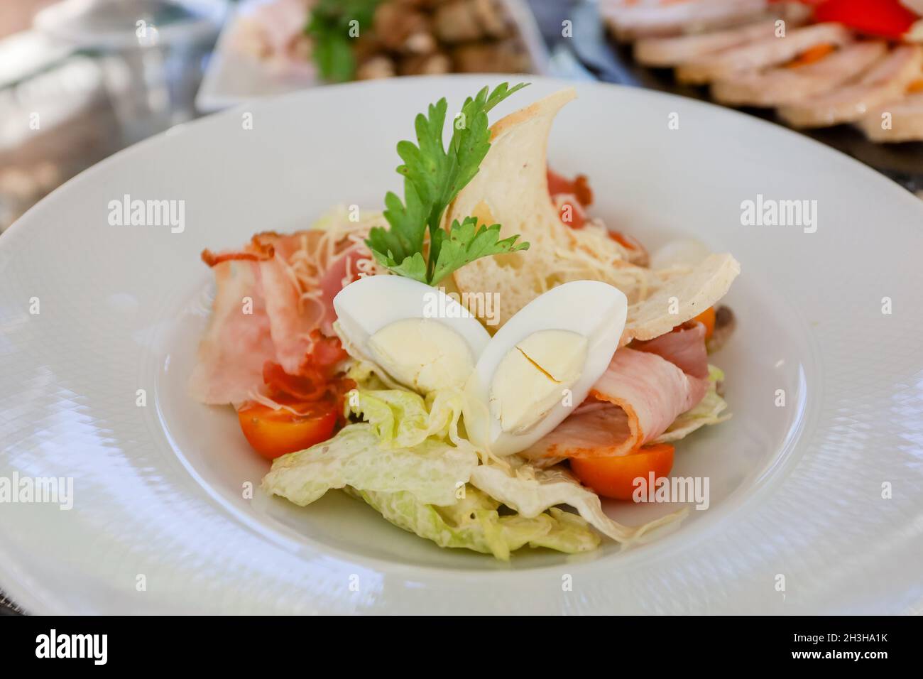 Œufs, croûtons, tomates, salade de jambon dans une assiette blanche sur une table.Photo de haute qualité Banque D'Images
