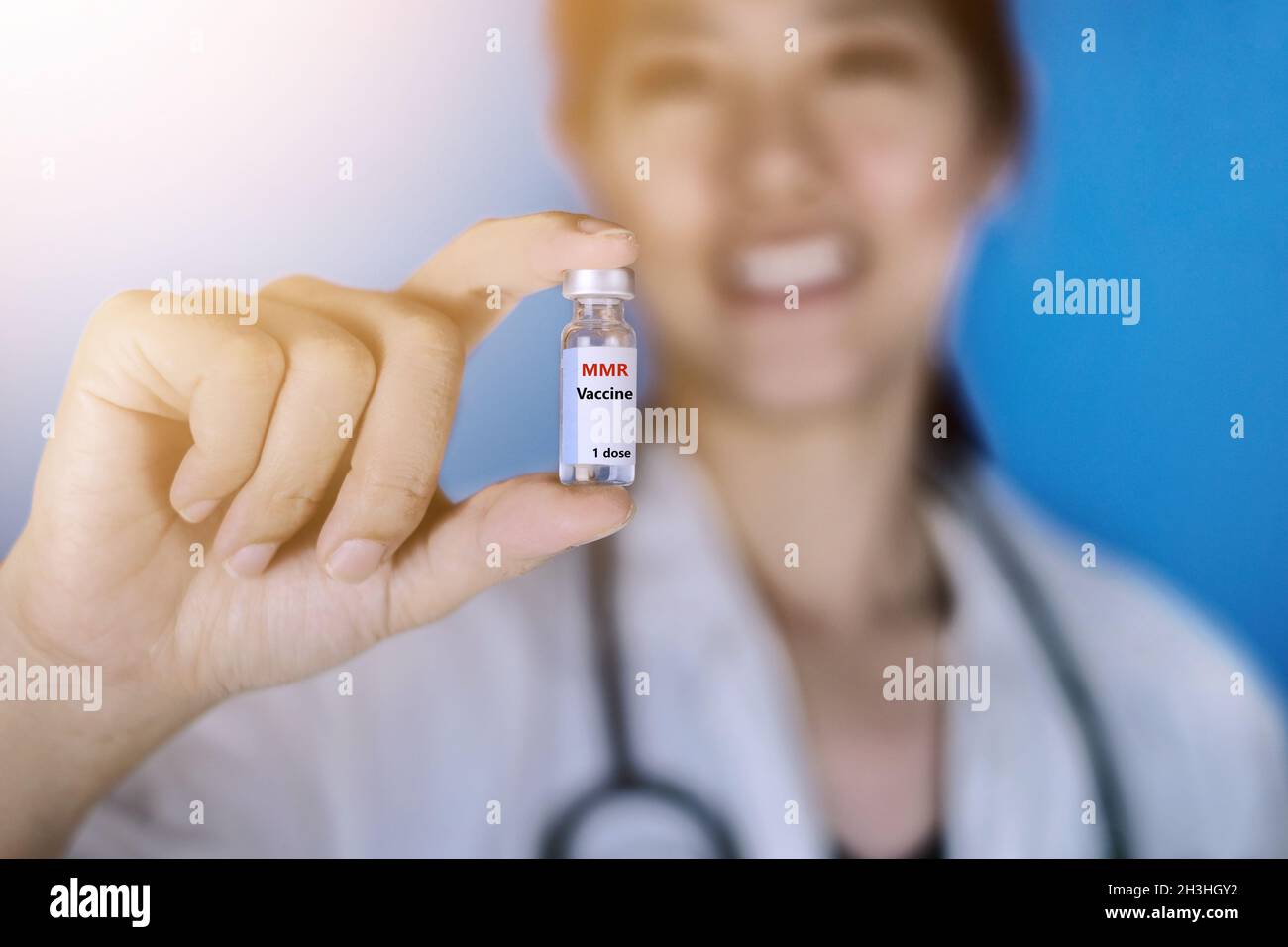 Vaccin RRO ou rougeole, oreillons et rubéole.Femme médecin portant un manteau blanc avec un stéthoscope autour de son épaule tenant un flacon en verre de M-M-R va Banque D'Images