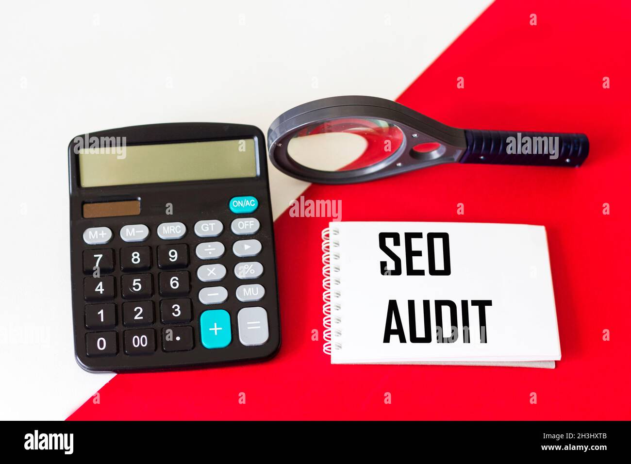 Texte écrit sur le bloc-notes, rapport d'audit SEO.La calculatrice et la loupe se trouvent sur un fond rouge et blanc.Site Web d'analyse conceptuelle Banque D'Images