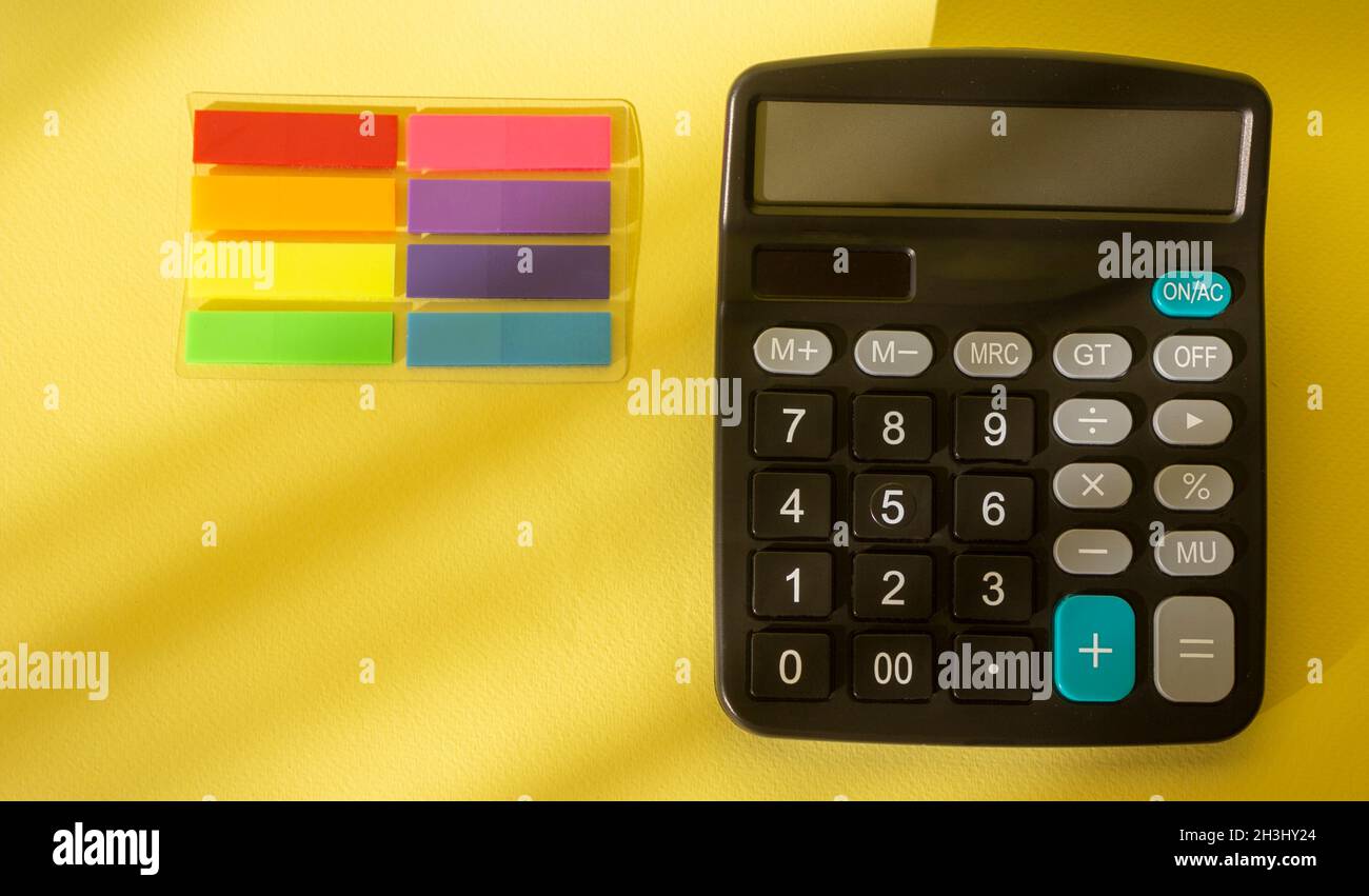 Vue de dessus de la calculatrice isolée sur fond jaune avec des autocollants de couleur Banque D'Images