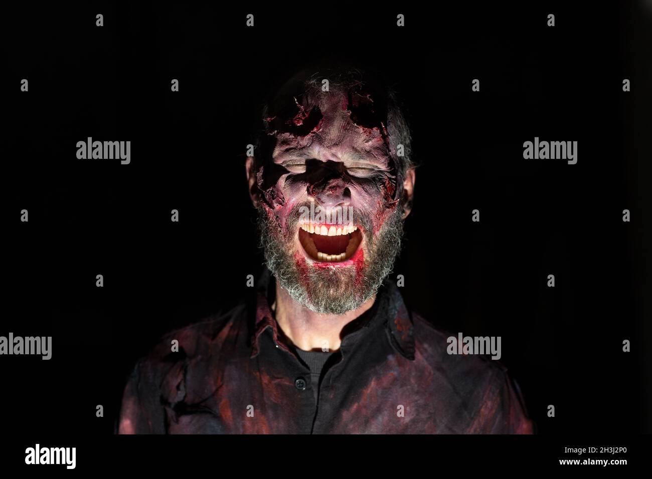 Portrait d'homme zombie dans l'obscurité avec maquillage pour la fête d'halloween Banque D'Images