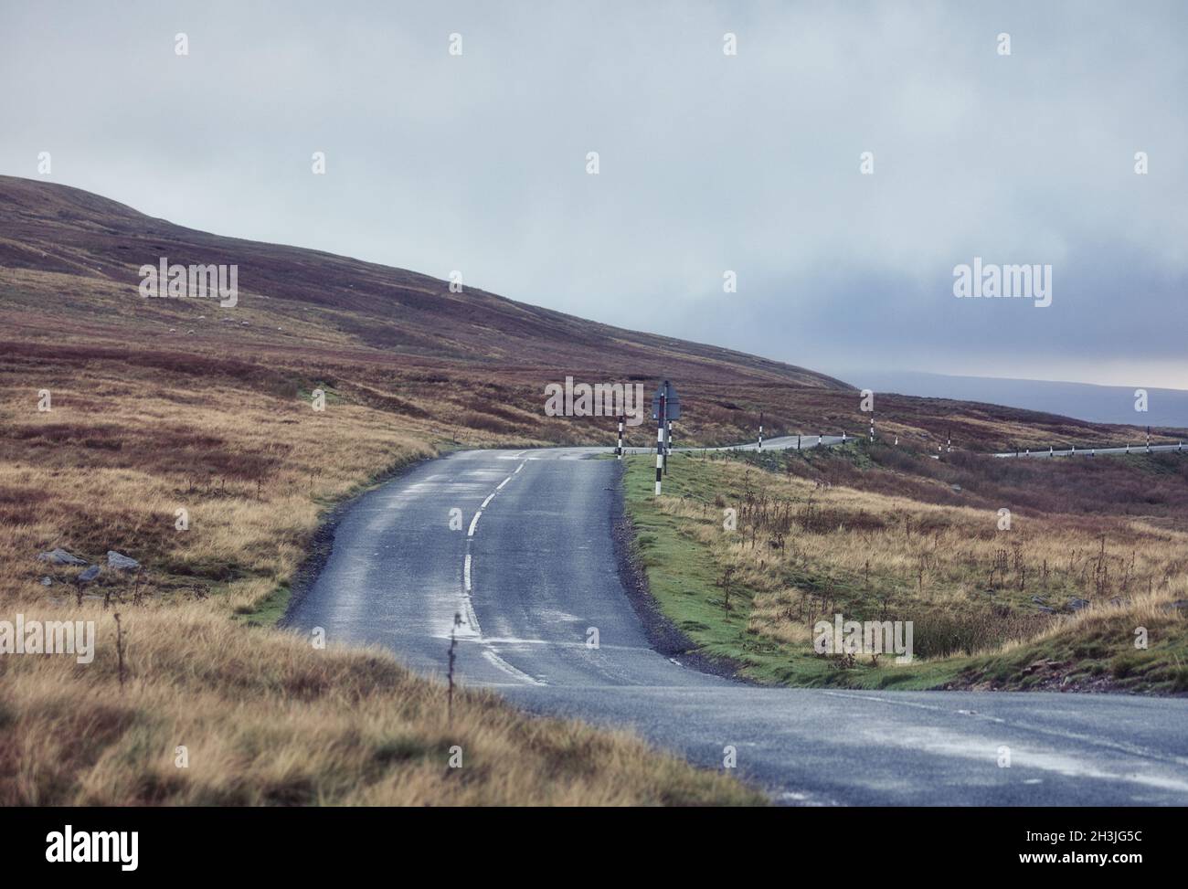 Route qui serpente à travers des moorland atmosphérique isolé et isolé, parc national de Yorkshire Dales, North Yorkshire, Angleterre Banque D'Images