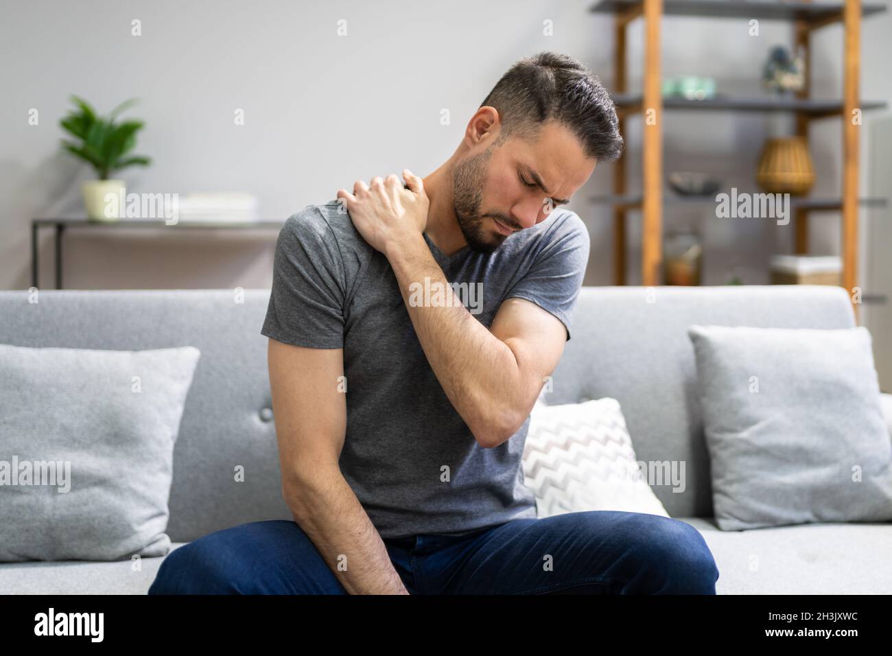 Homme souffrant de douleurs aux épaules à la table de traitement à domicile Banque D'Images