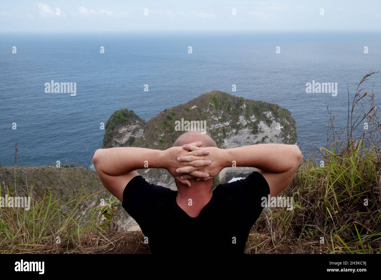 Homme assis sur la falaise et admirant la vue incroyable à Nusa Penida Banque D'Images