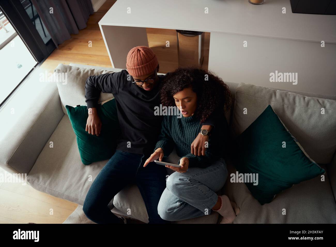 Vue panoramique d'un couple multiethnique heureux assis sur un canapé à l'aide d'une tablette électronique Banque D'Images