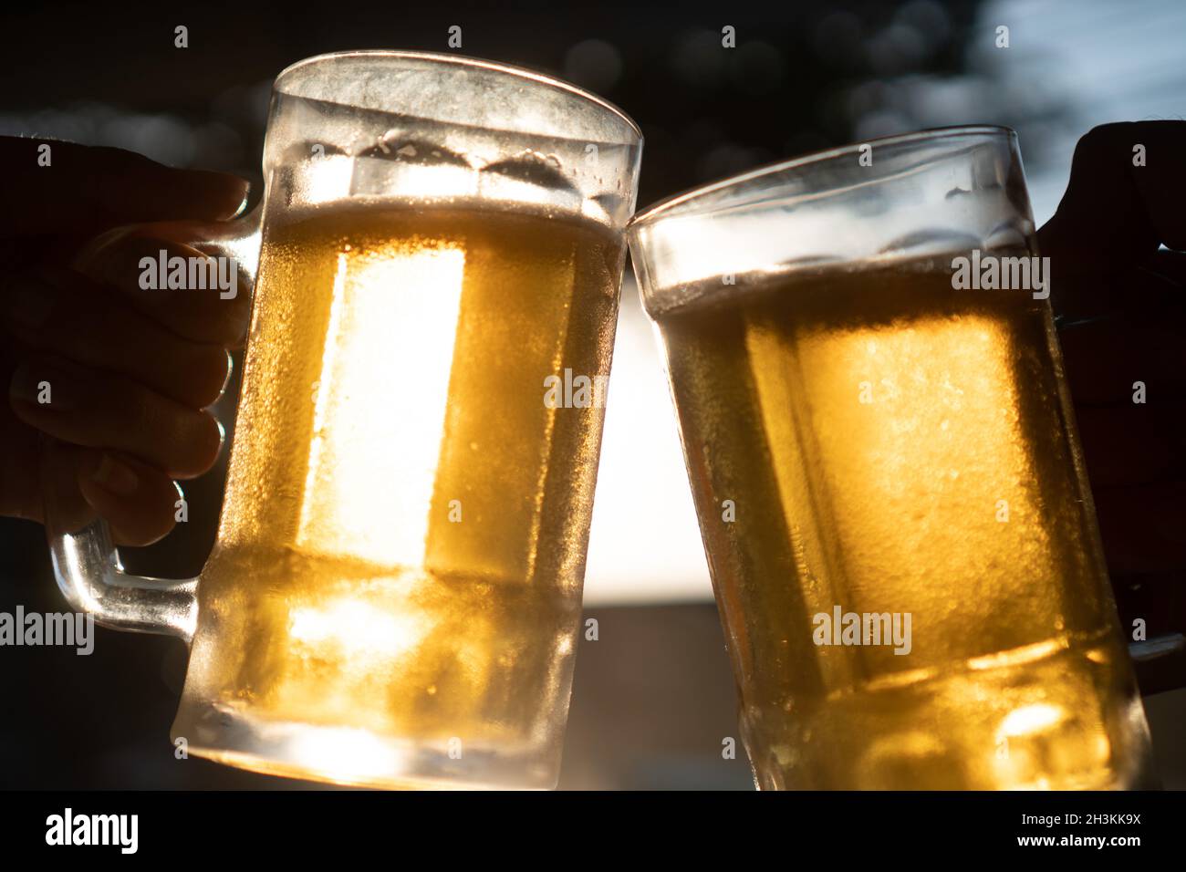 Gros plan toast trinking bière lager fraîche mugs avec des rayons du soleil dans la chaude journée d'été Banque D'Images