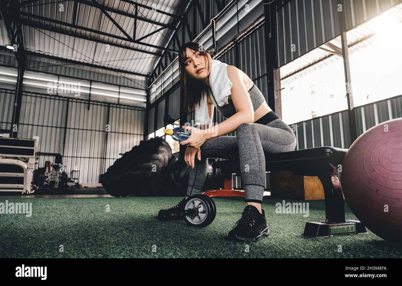 Belle femme de fitness assise sur une chaise et se reposant après l'entraînement au centre de fitness.Une femme fait une pause après un cardio dur Banque D'Images