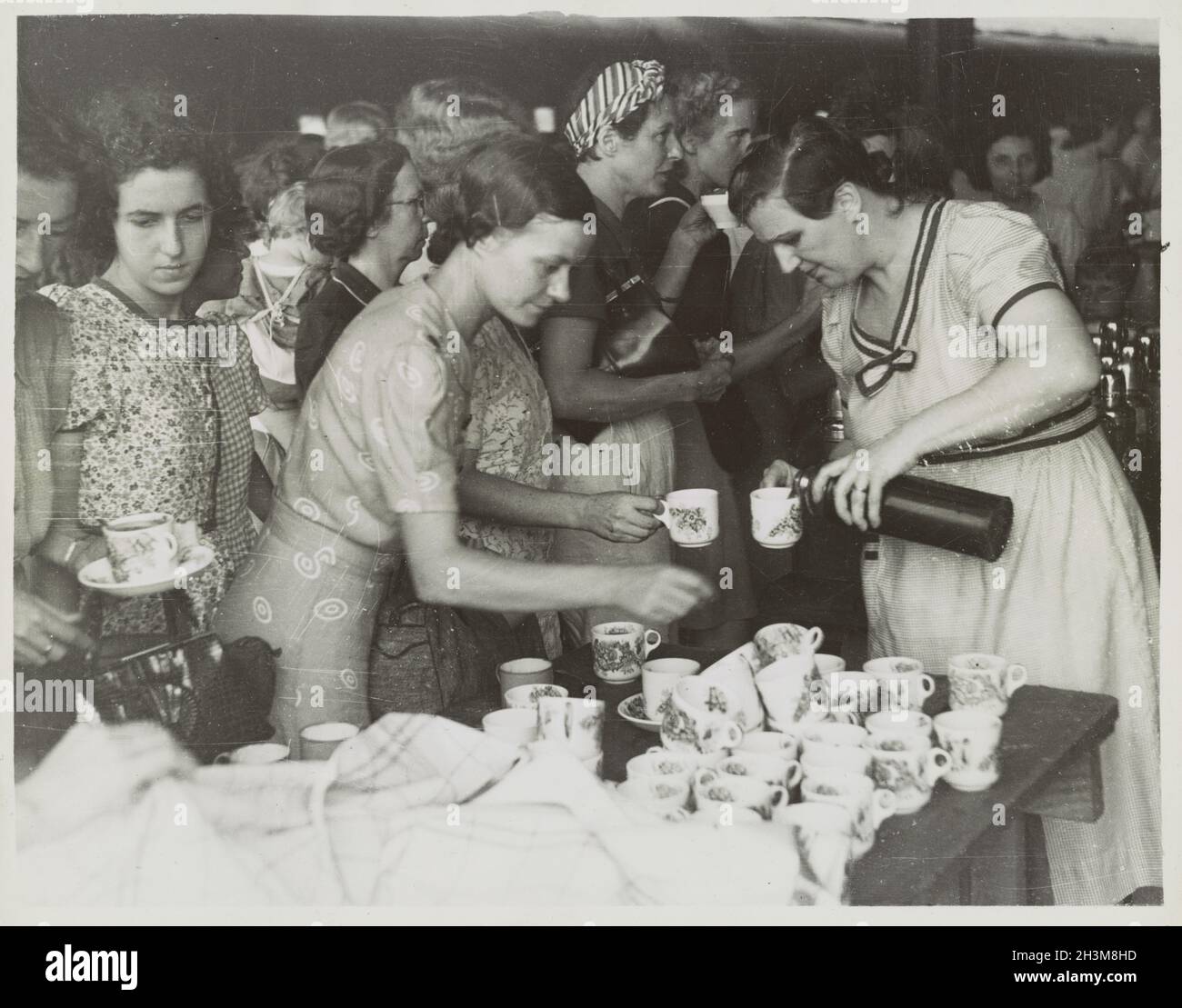 Une photo d'époque vers février 1942 montrant une femme à la gare d'Ipoh à Perak, en Malaisie, versant du thé pour un groupe de femmes réfugiées de Penang sur leur chemin vers Singapour pendant l'invasion japonaise de Malaya Banque D'Images