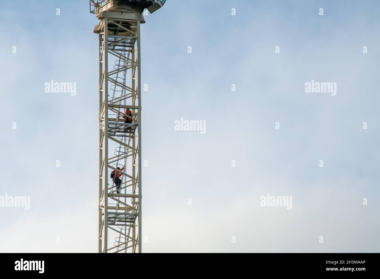 Deux opérateurs de grue à tour descendent les échelles du mât à la fin d'un quart de travail. Banque D'Images