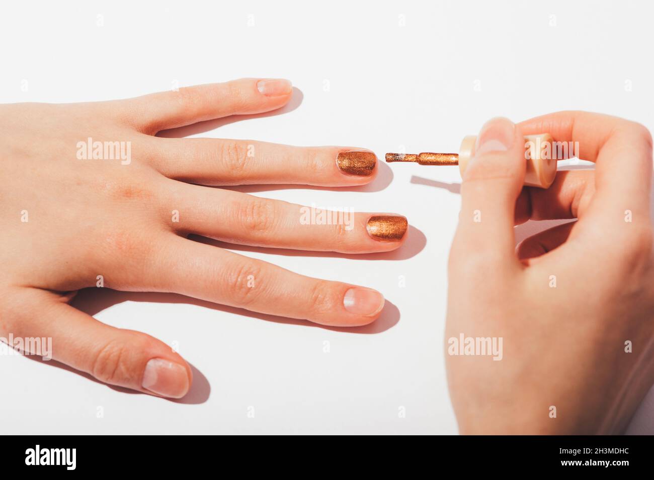 Femme mains faisant manucure avec vernis à ongles bronze brillant sur fond  blanc, gros plan Photo Stock - Alamy
