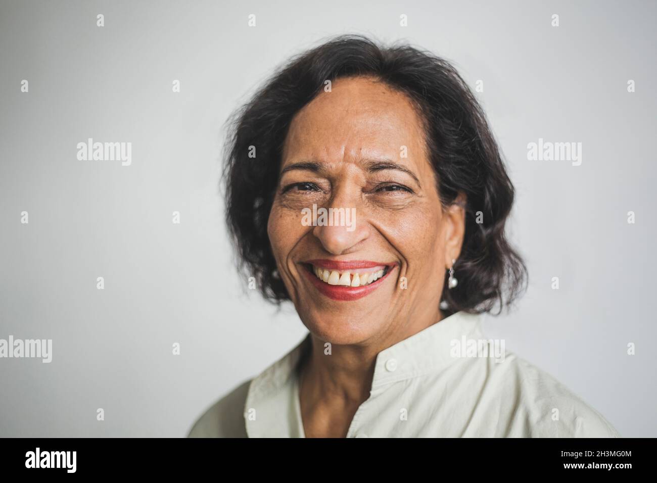 Portrait d'une femme âgée souriante contre le mur Banque D'Images