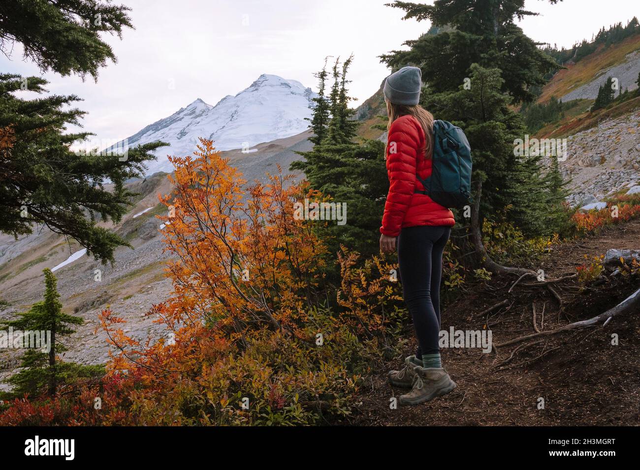 Randonnée féminine avec veste Red Puffy et sac à dos à Mount Baker Banque D'Images