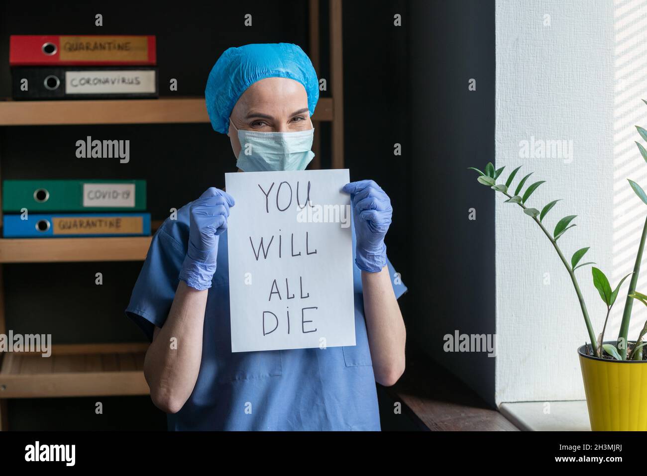 Mauvaise prévision ou perspectives du médecin.Infirmière souriante sarcastique en uniforme de protection tient une feuille de papier avec l'inscripti Banque D'Images