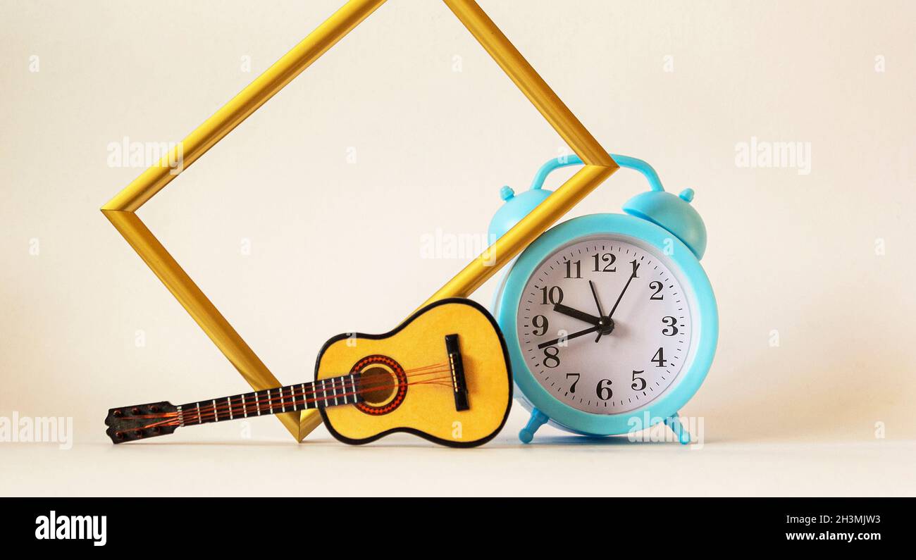 Guitare jouet, réveil bleu et cadre doré sur fond blanc Photo Stock - Alamy
