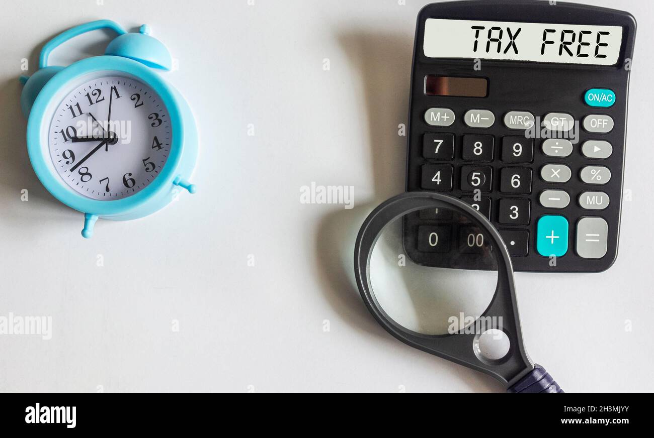 Calculatrice avec le texte Tax Free sur fond blanc avec un réveil et une loupe. Banque D'Images