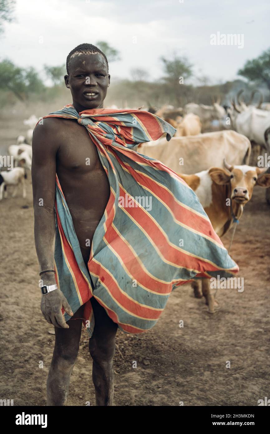 Tribu MUNDARI, SOUDAN DU SUD - 11 MARS 2020 : un jeune homme berce dans des vêtements colorés qui regardent la caméra avec méfiance pendant Banque D'Images