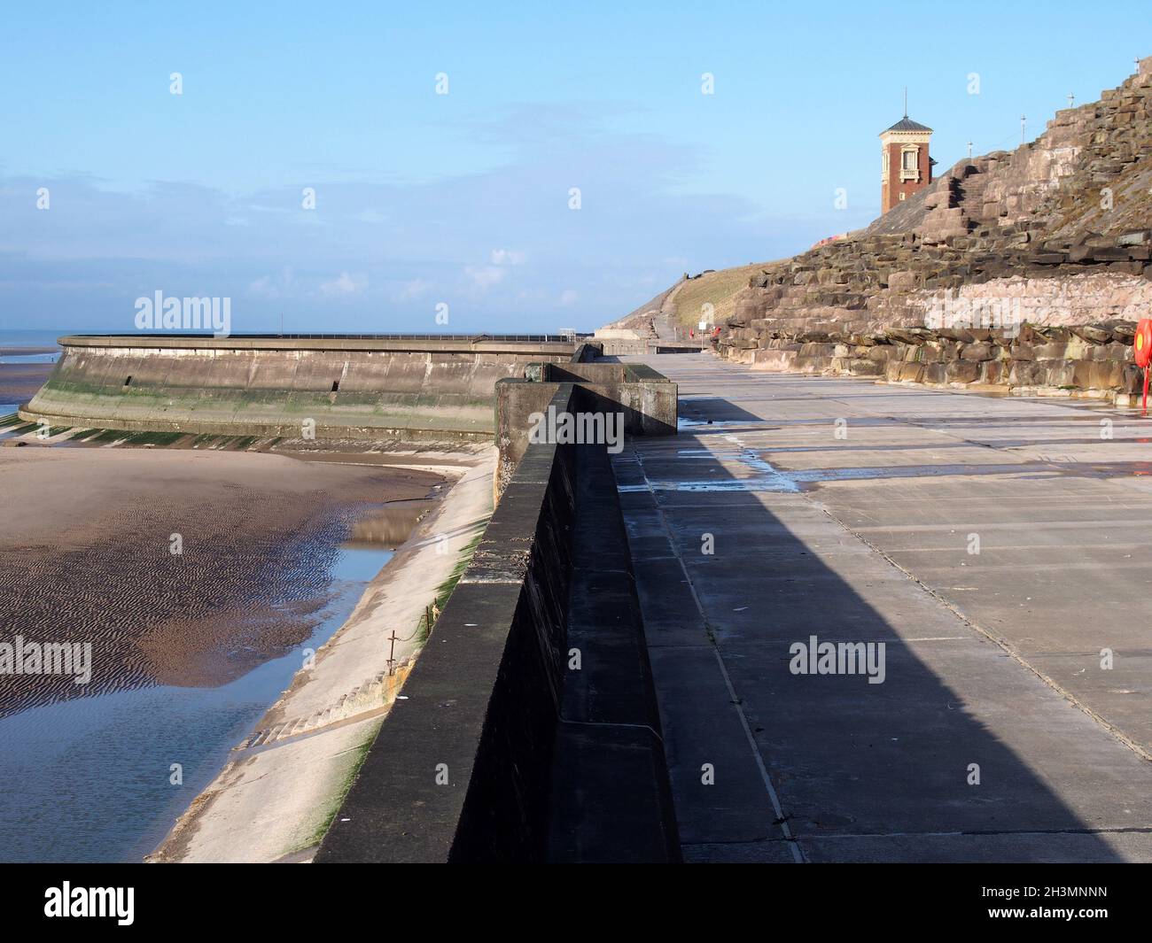 Escaliers en béton sur la digue de blackpool avec la plage à marée basse en plein soleil avec la vieille piscine et la tour de bateau dans la différence Banque D'Images