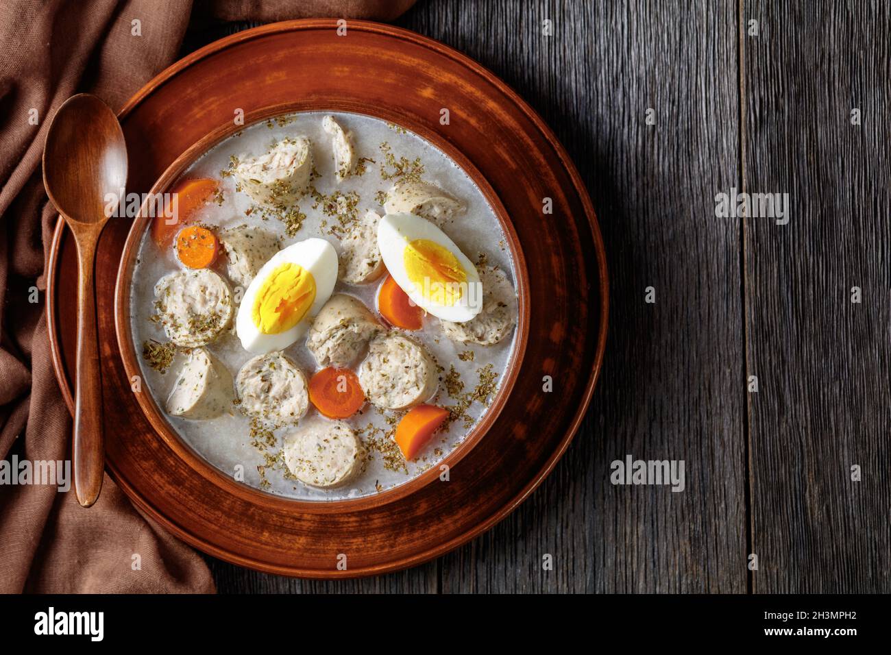 Soupe de seigle fermentée à polir Zurek avec kielbasa blanc poli traditionnel ou saucisse avec marjolaine, œufs durs servis sur un bol en argile avec un bois Banque D'Images