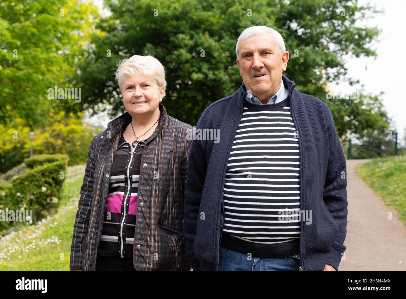 Un couple de personnes âgées se promenant dans le parc pose pour la caméra.Femme aînée tenant le bras de son mari à l'extérieur.Société, concepts de support Banque D'Images