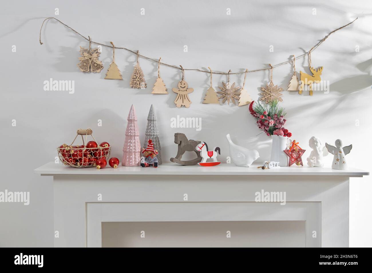 Décoration de l'intérieur de l'appartement pour Noël.Une guirlande de figurines en bois sculpté.Bougies et figurines en céramique sur une fausse cheminée.Copie s Banque D'Images