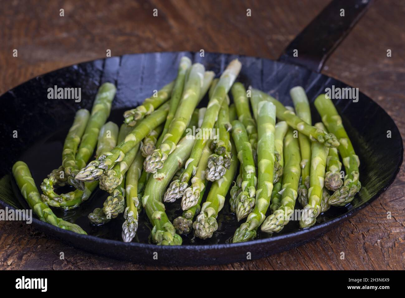 Asperges vertes fraîches dans une poêle sur bois sombre Banque D'Images