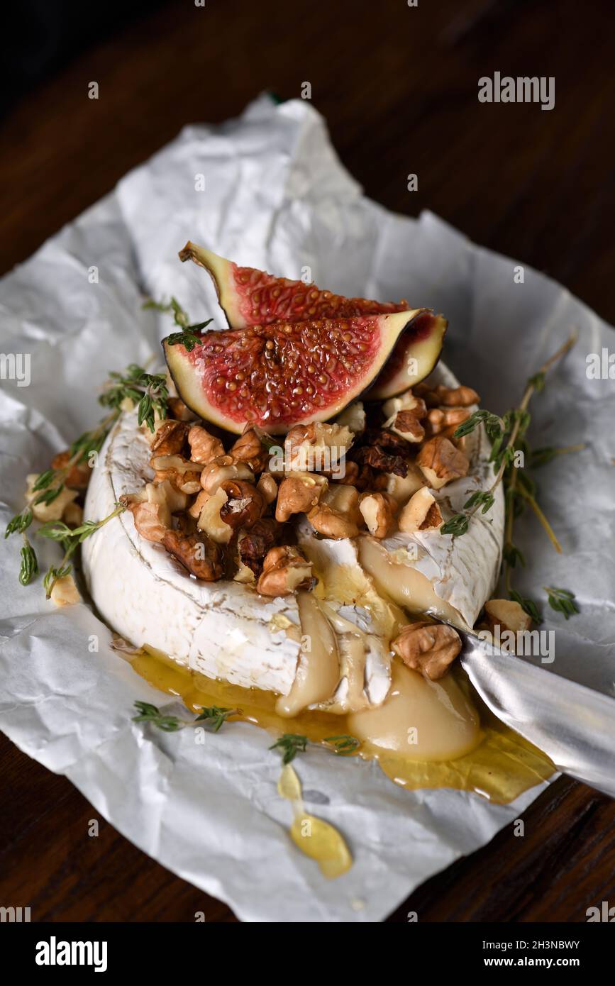 Camembert cuit avec des noix et du miel, des tranches de figues et de thym. Banque D'Images