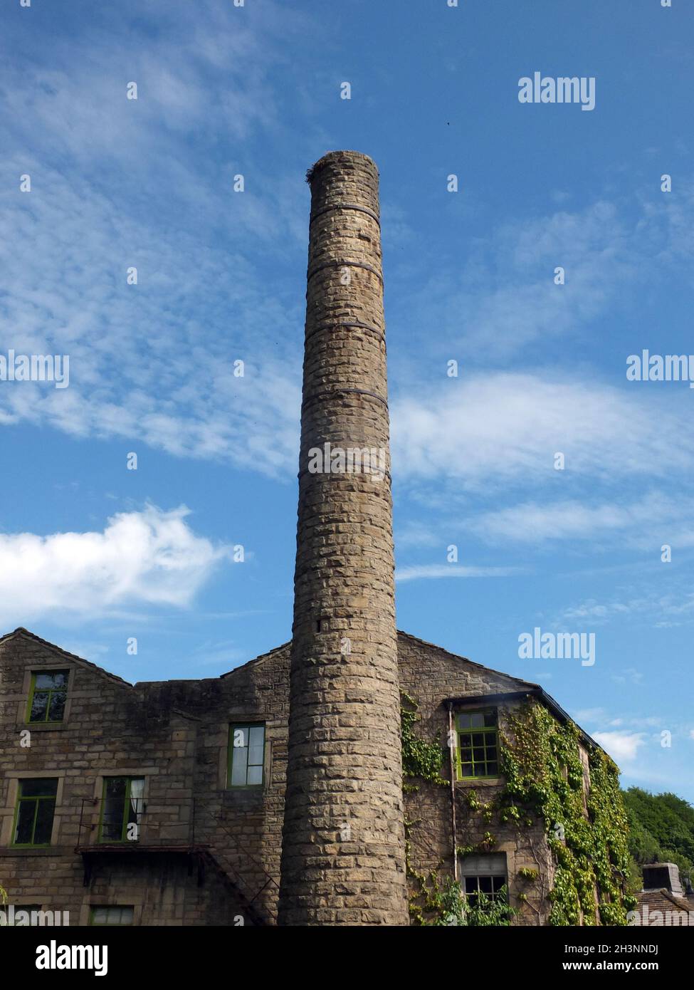 Ancien moulin et grande cheminée avec ciel bleu nuageux dans le pont hebden West yorkshire Banque D'Images