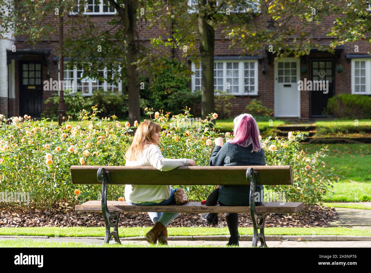 Jeunes femmes qui discutent dans les jardins de Port Sunlight, King George's Drive, Port Sunlight, Metropolitan Borough of Wirral, Merseyside, Angleterre, Royaume-Uni Banque D'Images