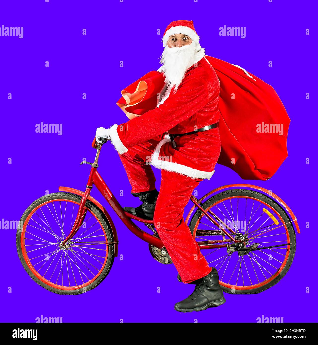 Le joyeux Père Noël dans un chapeau du nouvel an et des vêtements de costume rouge se promette à vélo avec un sac de cadeaux.Trois isolats sur fond blanc.Bonne nouvelle oui Banque D'Images