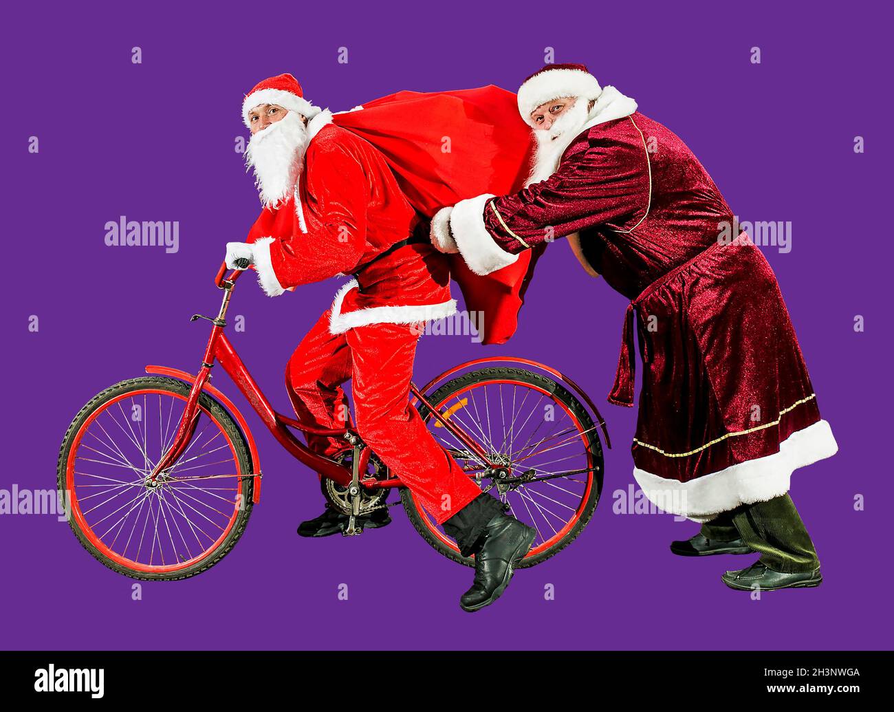 Deux clauses de Noël joyeux dans les chapeaux du nouvel an et les costumes rouges sont à cheval sur un vélo avec un sac de cadeaux.Isoler.Bonne année 2022.Joyeux Noël.Conc Banque D'Images