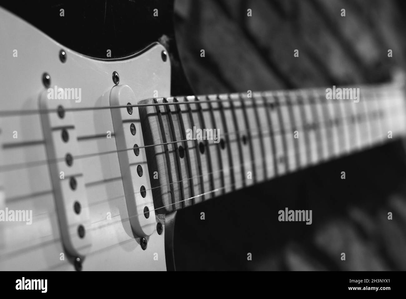 Guitare accrochée sur un mur de briques.Concept de décoration de magasin de musique.Photographie en noir et blanc Banque D'Images