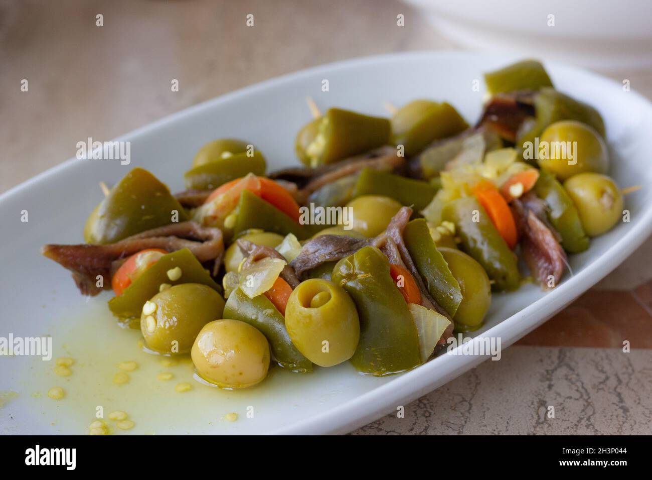 Hors-d'œuvre épicés avec olives vertes, anchois et jalapeños sur l'assiette.En-cas traditionnel basque gildas pintxos Banque D'Images